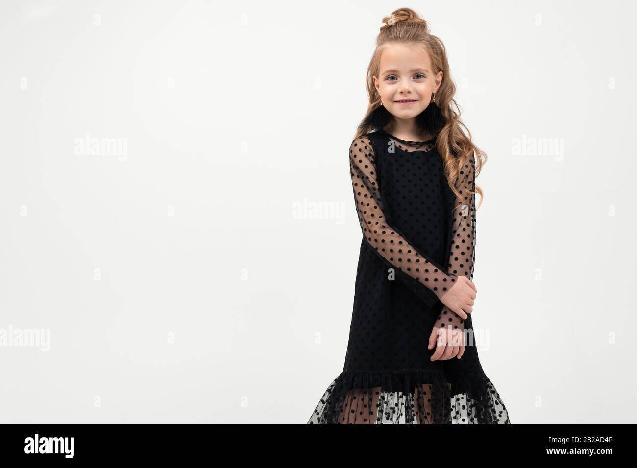 Pretty little girl in black dress stands isolated on white background ...