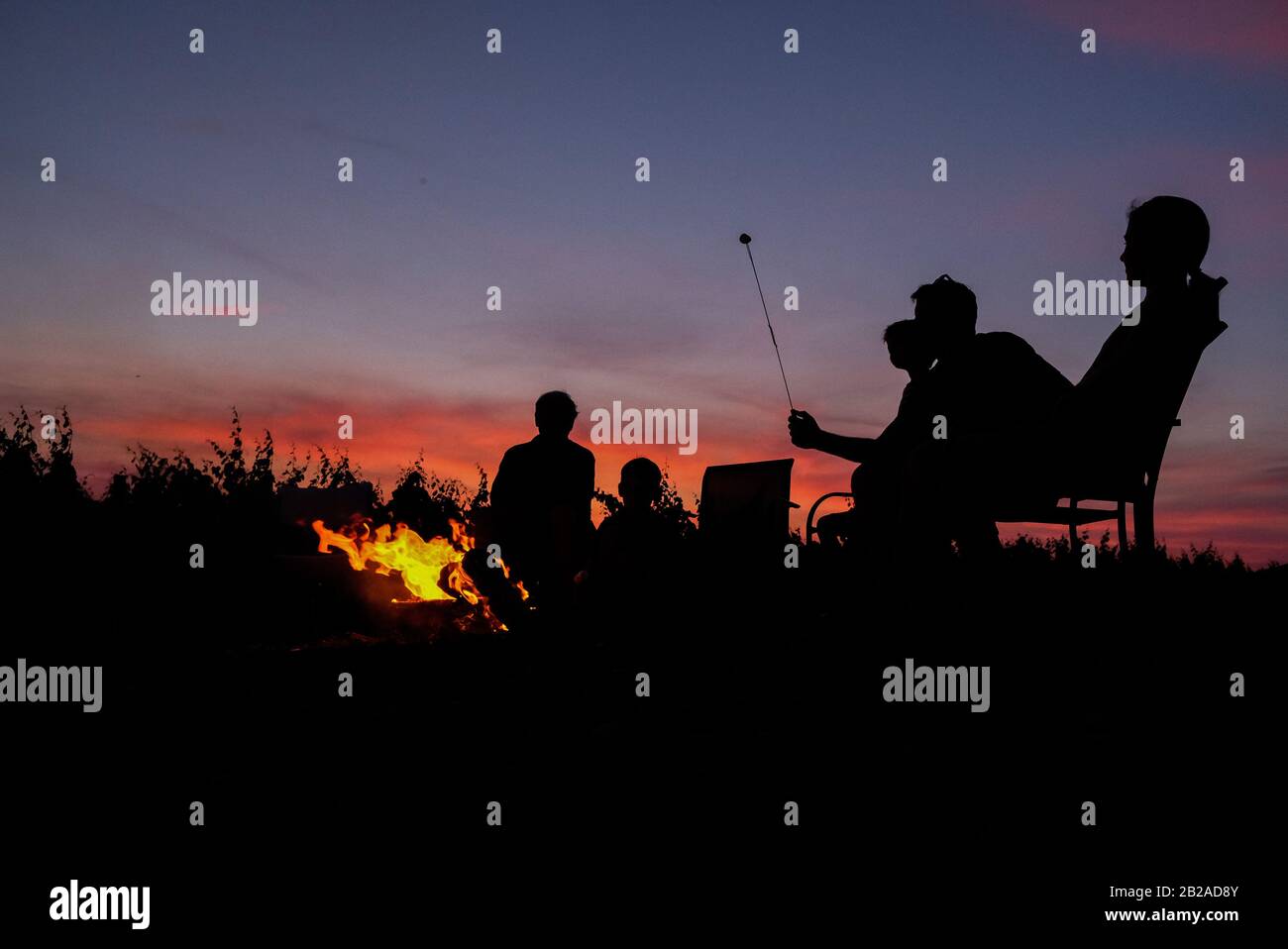 Silhouette of a family toasting marshmallows around a fire pit, USA