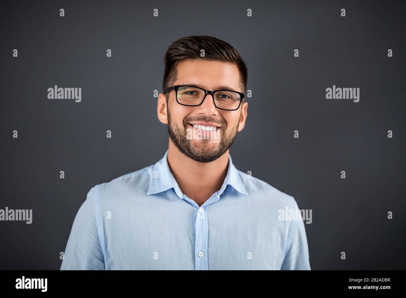 Handsome man standing over dark grey background and looking on camera. Portrait man concept. Stock Photo