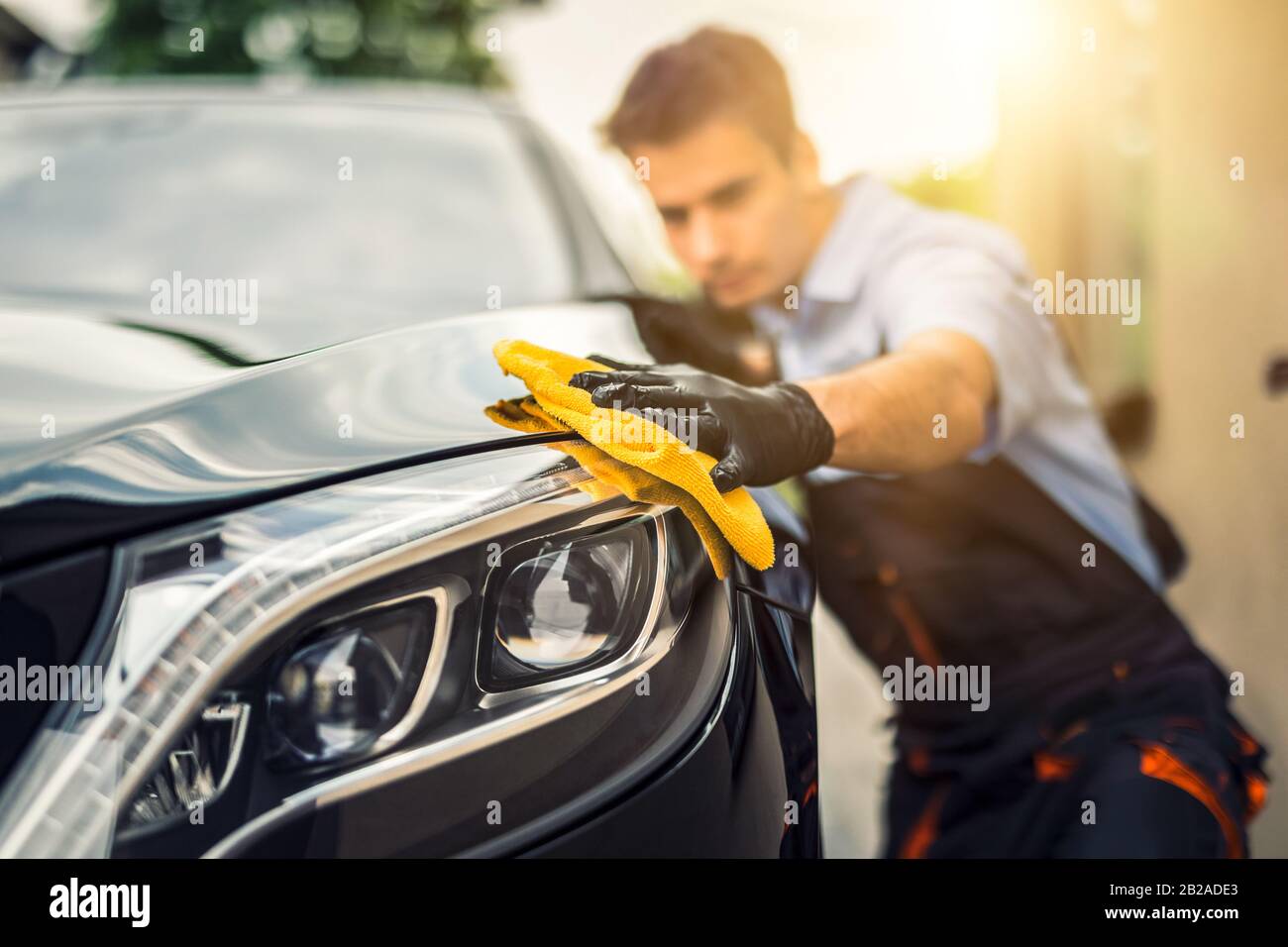 Car detailing - the man holds the microfiber in hand and polishes the car. Selective focus. Stock Photo