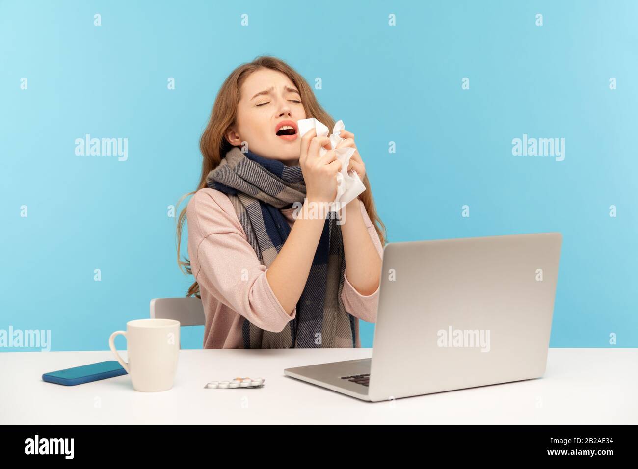 Flu-sick girl sneezing in tissue, ill freelance woman coughing suffering fever, seasonal influenza symptoms while working on laptop at home office, sy Stock Photo