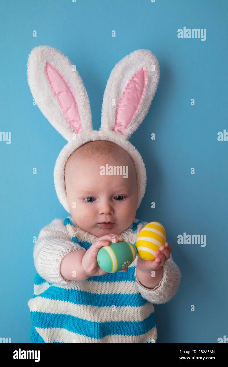 Cute baby wearing easter bunny ears surrounded by easter eggs Stock