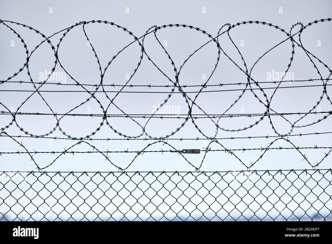 Close-up of a high chain-link fence with razor-barbed wire at the top protecting an airport in Germany Stock Photo