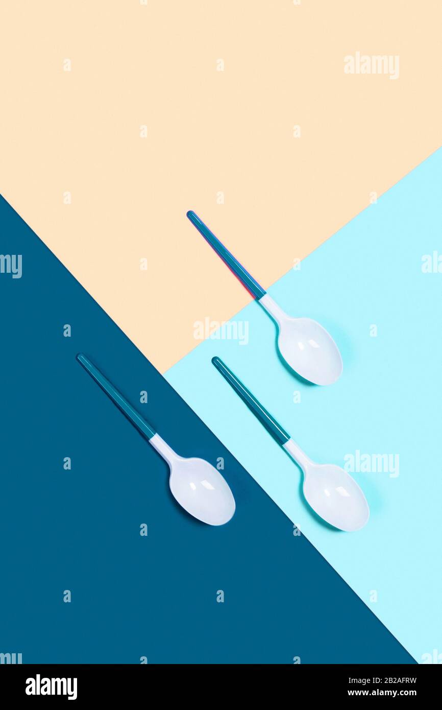 Dangerous three plastic spoons. Tricolor background. Flat lay, top view