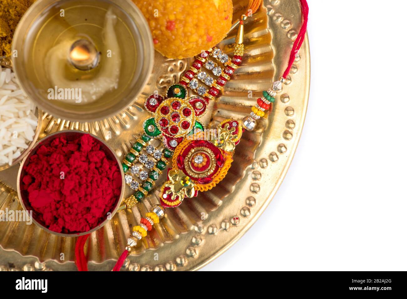 Indian Festival Rakhi with rice grains, kumkum, sweets and diya on