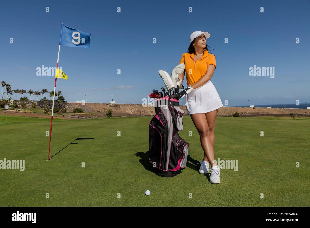 Woman in stylish summer golf outfit standing with bag of drivers on  beautiful green course for golf game Stock Photo - Alamy