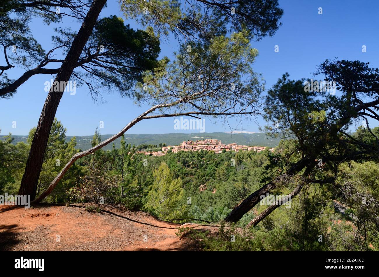 Landscape with Ochre Outcrops & Pine Trees Framing the Perched Village of Roussillon in the Luberon Regional Park Vaucluse Provence France Stock Photo