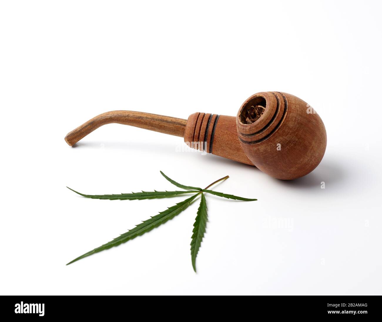wooden smoking pipe and green hemp leaves on a white background