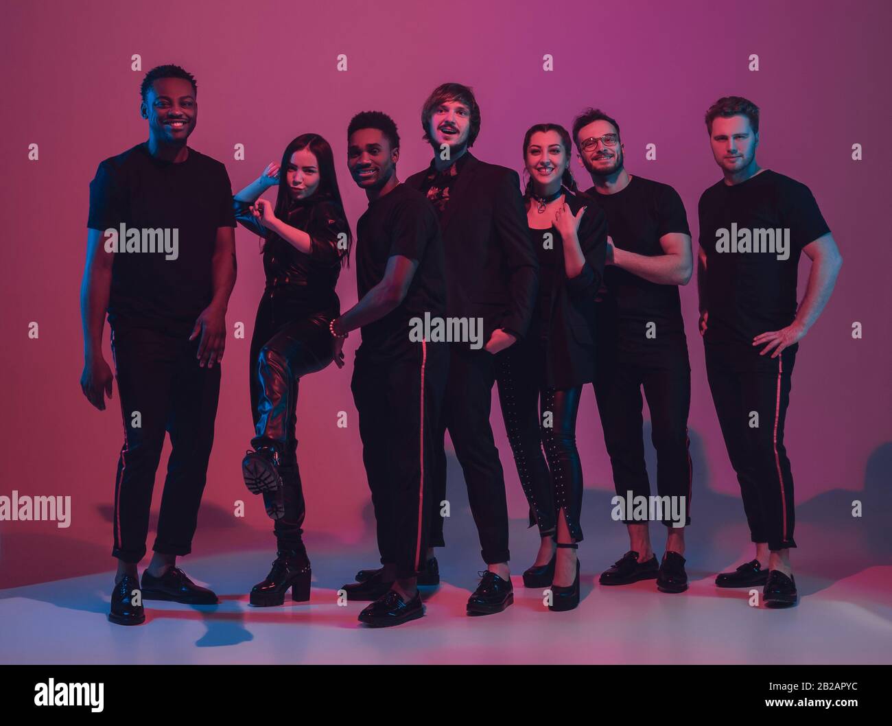 Group of young multiethnic musicians created band, dancing in neon ...