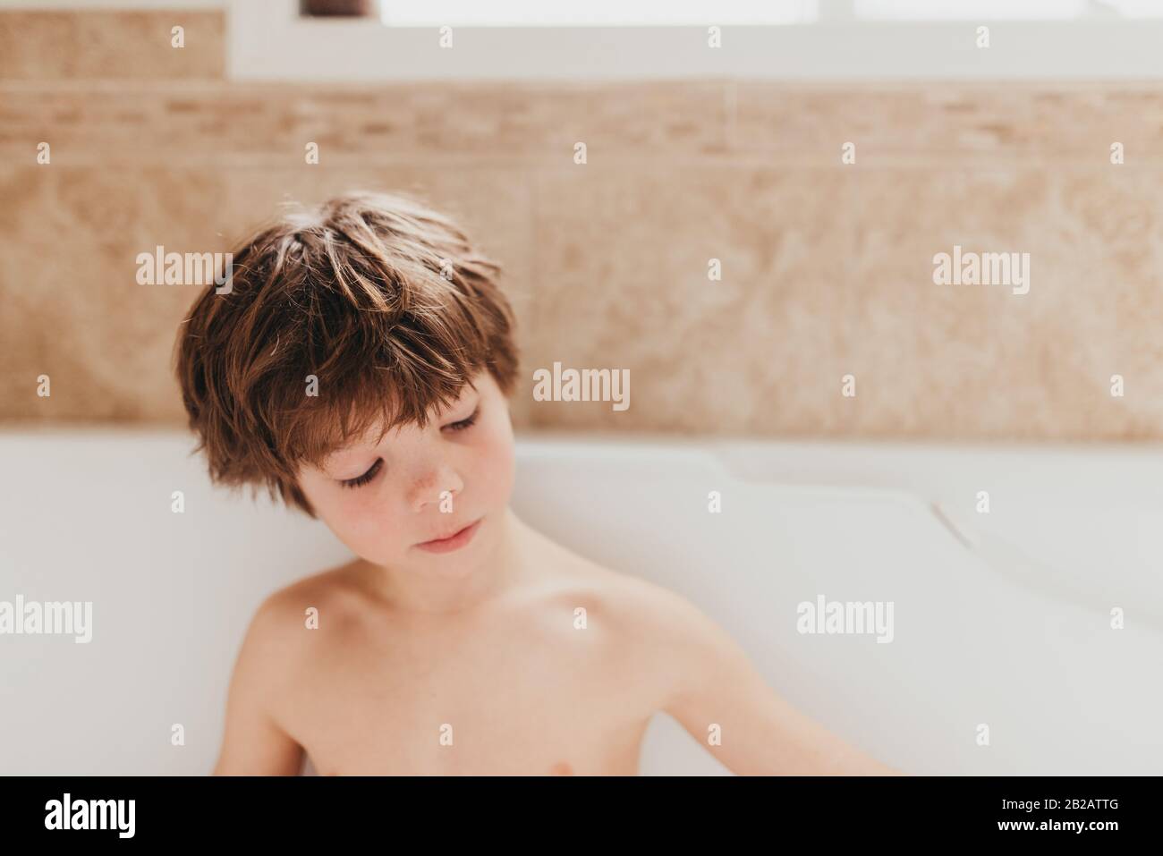 Portrait of a young boy sitting in a bubble bath Stock Photo