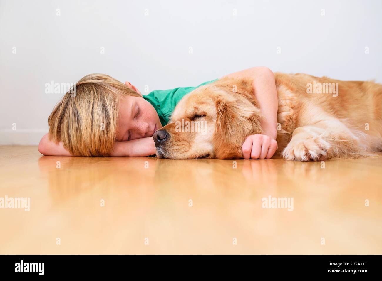 Boy lying on the  floor cuddling a golden retriever dog Stock Photo