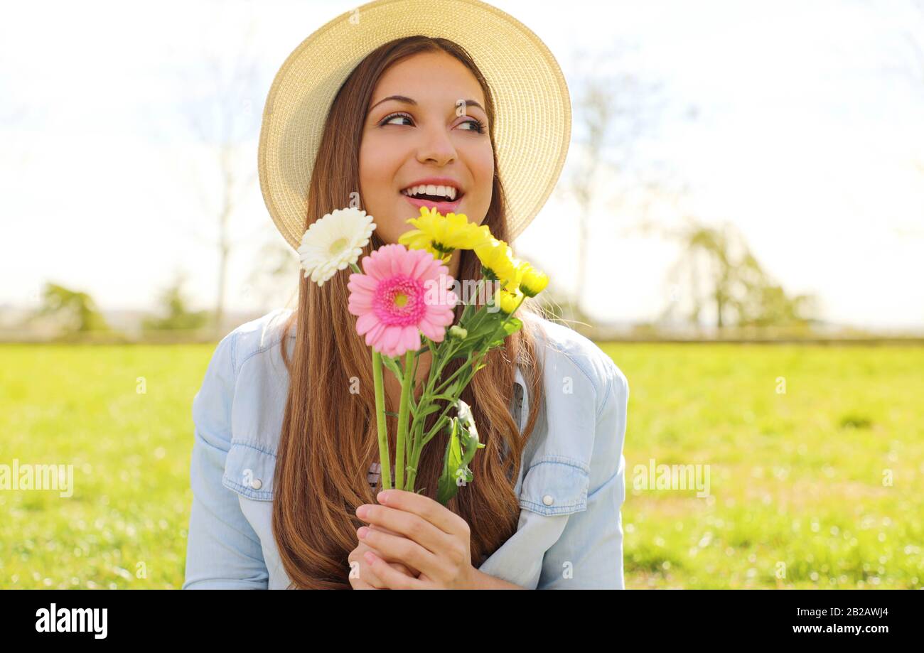 Smiling girl with flowers bouquet looking to the side outdoor in park Stock Photo