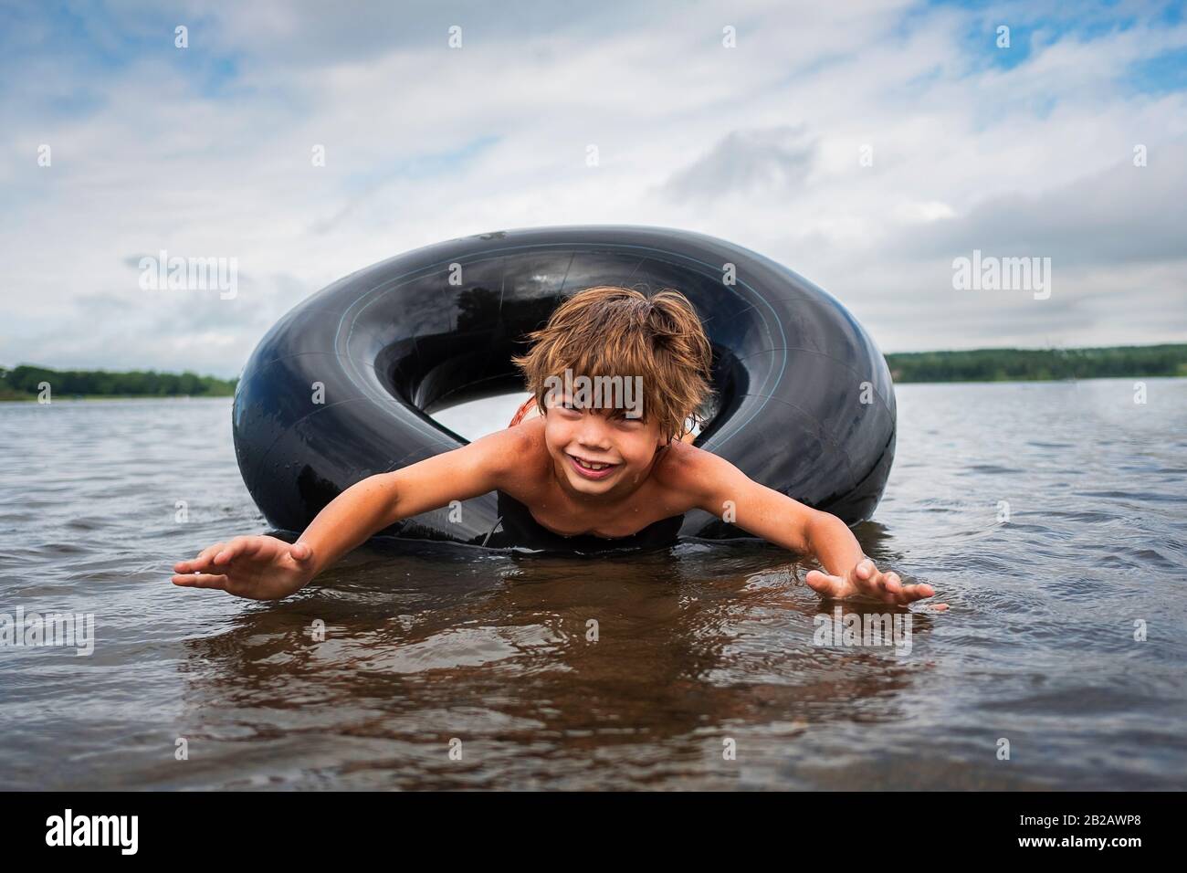 Happy boy floating in an inflatable rubber ring in a lake, USA Stock Photo