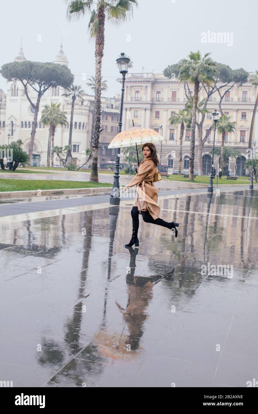 Woman running through the city in the rain, Rome, Lazio, Italy Stock Photo