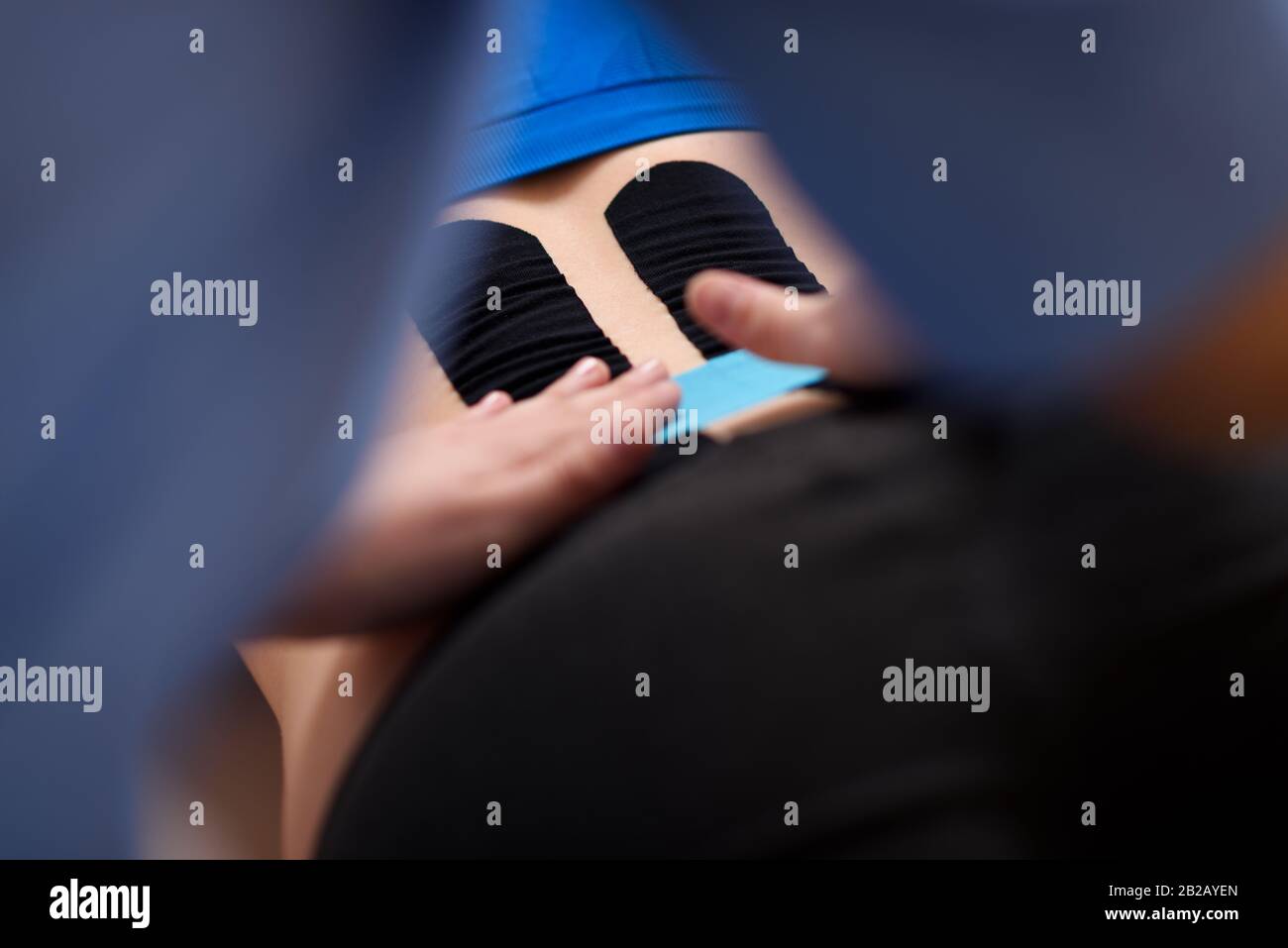 Physical therapist applying kinesio tape on female patient's lower back