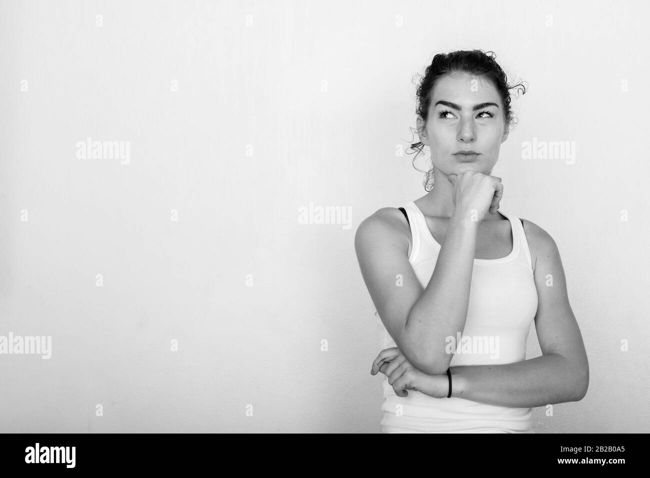 Studio shot of beautiful teenage girl thinking while looking up against ...