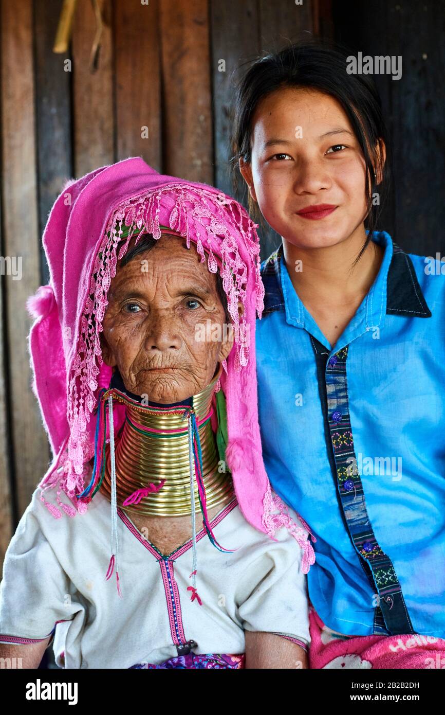 Portrait of an old Kayan Lahwi woman with brass neck coils and traditional clothing with her grand daughter, who does not wear the rings. The Long Stock Photo