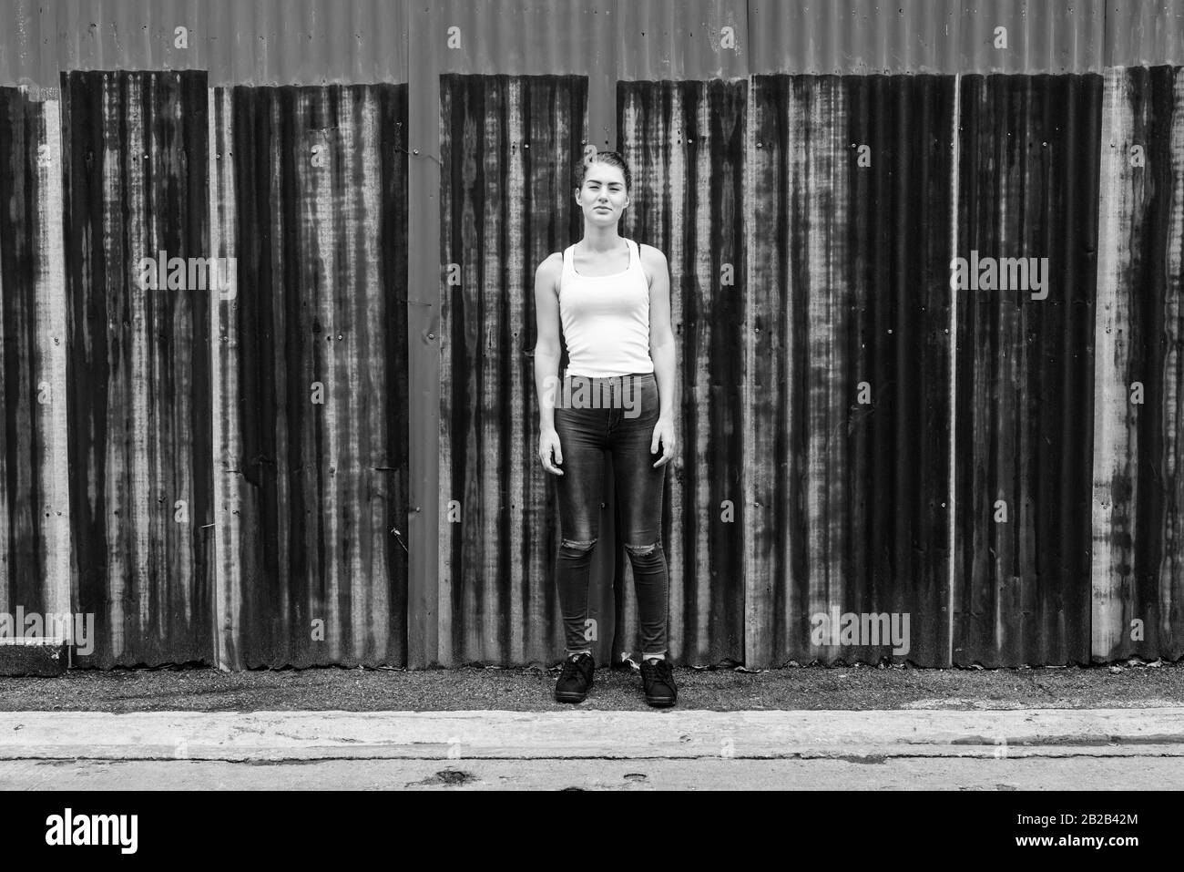 Young beautiful teenage girl standing against old rusty sheet wall Stock Photo