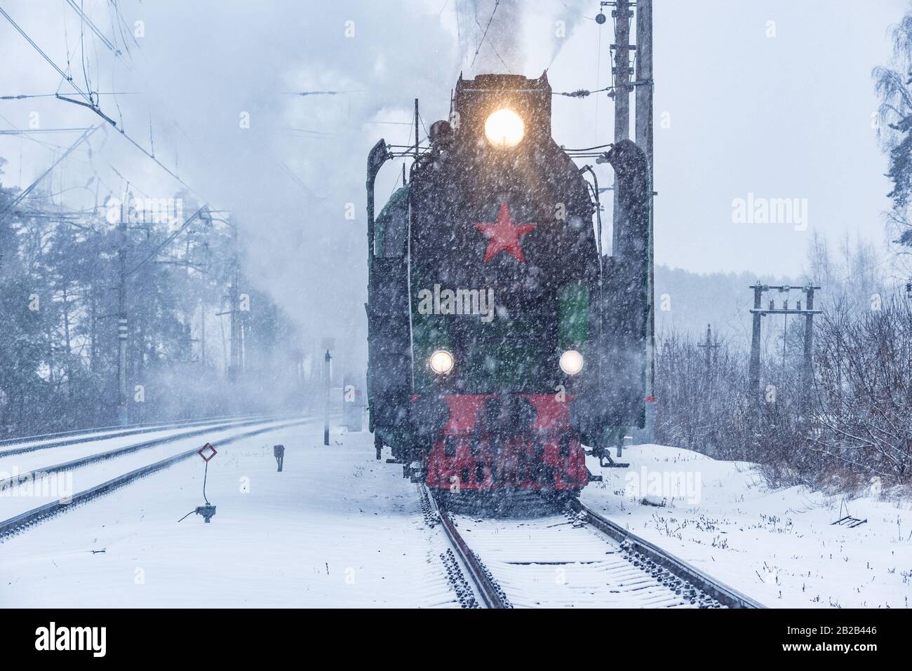Retro steam train departs from the railway station at winter snowy time ...
