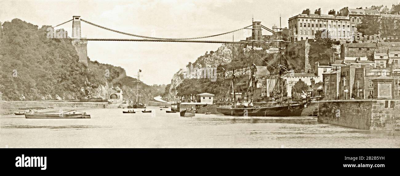 Clifton Suspension Bridge above the Avon Gorge, Bristol, England, UK c.1880. This view is looking west, down the Avon from the Bristol side of the bridge with a busy river traffic below the bridge and sailing ships moored. The bridge was designed by Victorian engineer Isambard Kingdom Brunel and work began in 1831 on the twin towers. Money problems meant that by 1843 only the stone towers were in place. After Brunel's death in 1859 the plans were revised and work began again. Clifton opened to traffic in 1864. Stock Photo