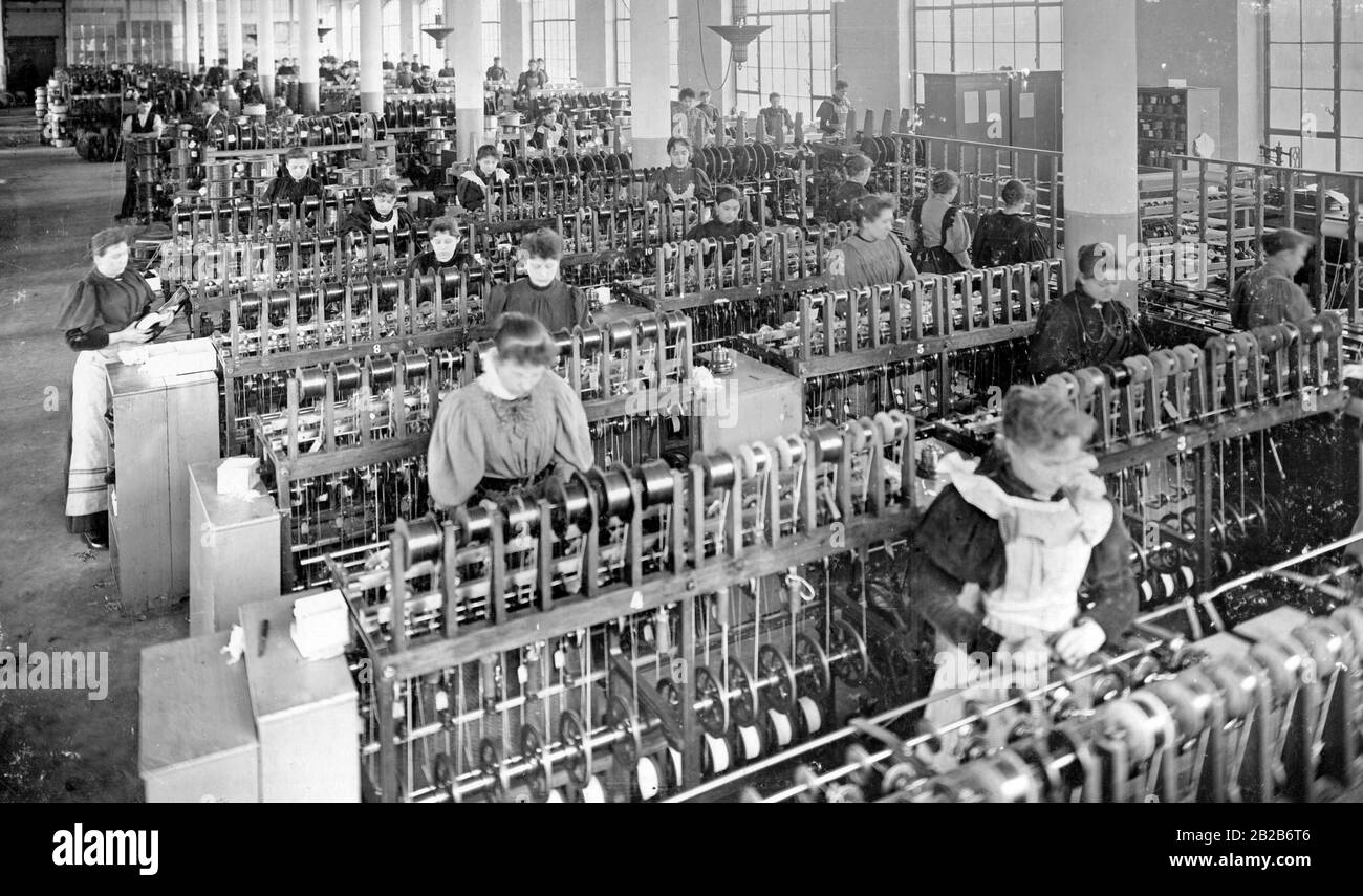 Women work on their machines in the wire spinning section of a cable factory. Stock Photo