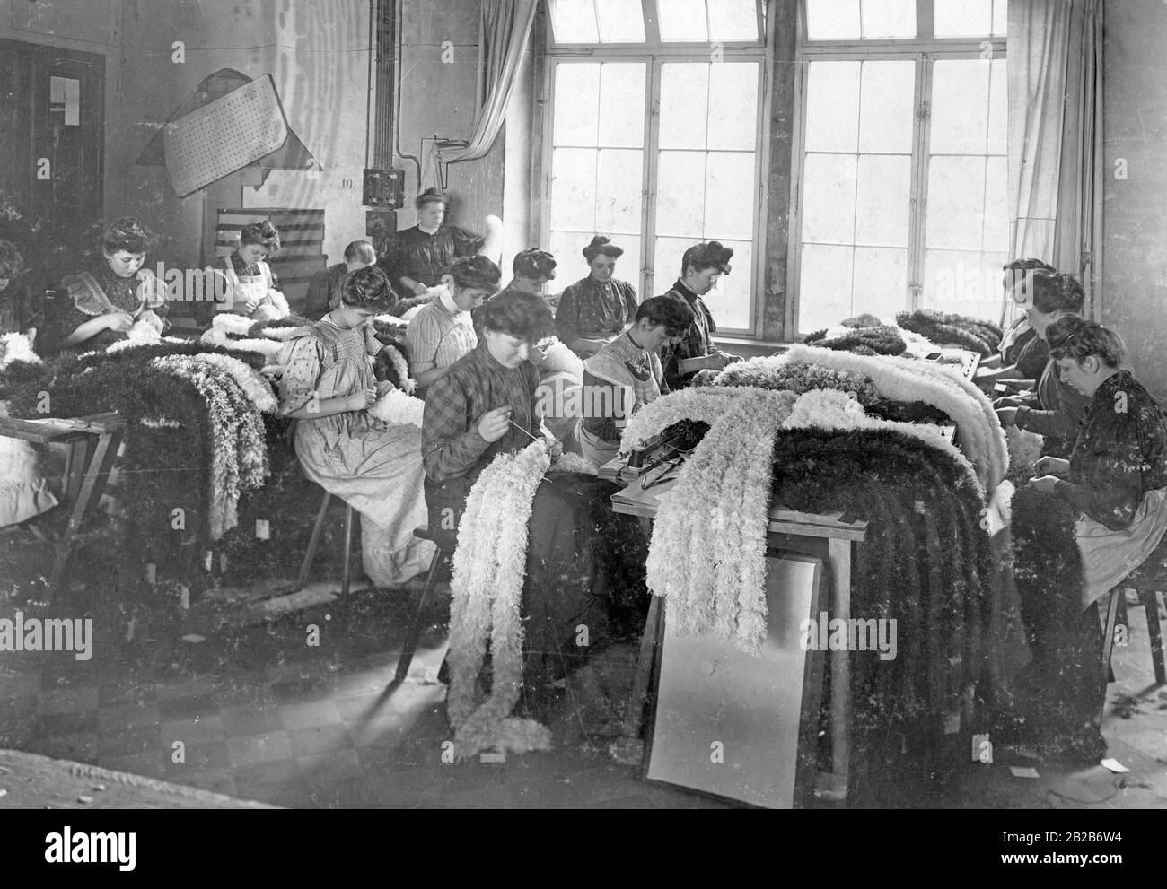 Women gather and sew decorative feathers in a factory. Stock Photo
