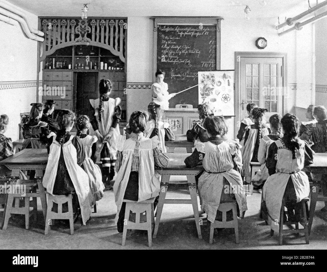 The education of girls during the Empire was supposed to prepare the future housewives for their three main tasks, then called the three big 'K's': church, kitchen, children. The food education shown in this photo, as taught in a new community school in Berlin in 1908, was considered a major step forward. Stock Photo