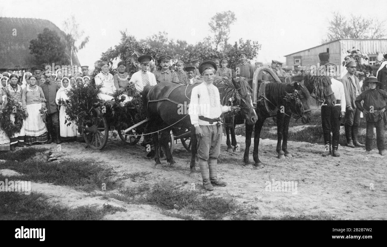 Harvest festival in Ukraine. Locals in their traditional costumes parade behind a horse and cart. German soldiers also joined the parade. Stock Photo