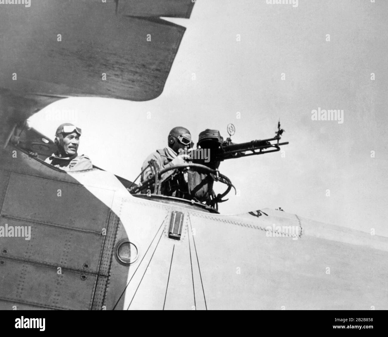 A Japanese bomber is in readiness on an airfield before an air attack on Chinese troops. The pilot turns to his gunner as he fires a volley from his machine gun. Stock Photo