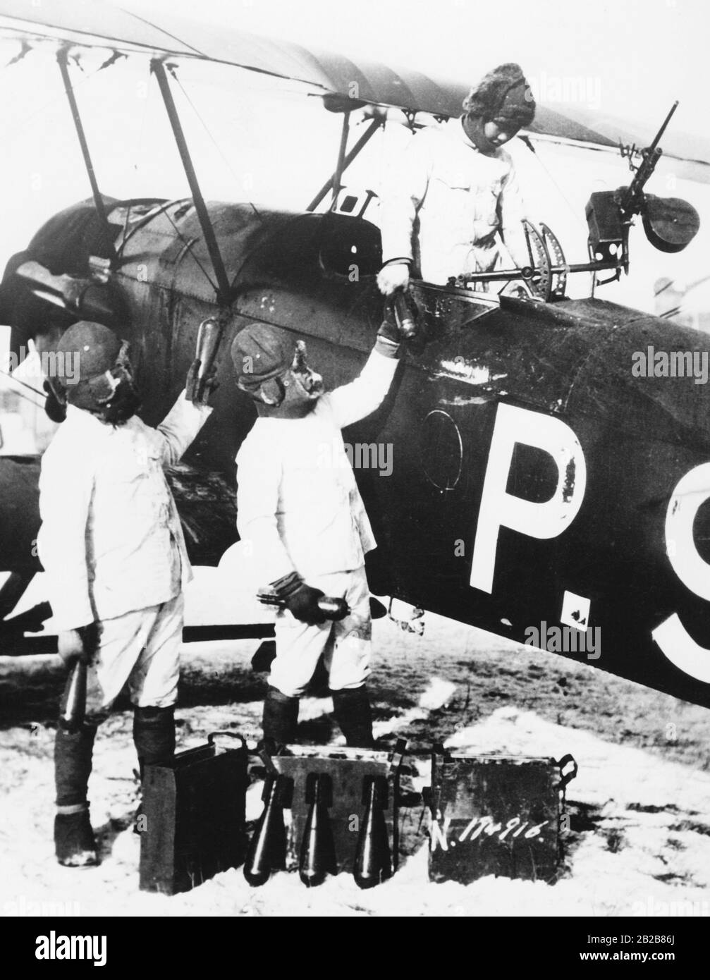 A Japanese fighter plane is loaded with bombs by three soldiers. These are later thrown out of the plane by hand during the flight. Stock Photo