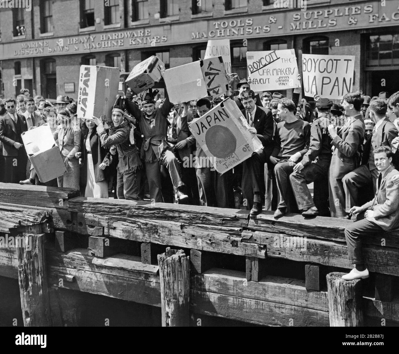 Students stand at the pier of the port in Boston and re-enact the Boston Tea Party of December 16, 1773 with products from Germany, Italy and Japan. Stock Photo