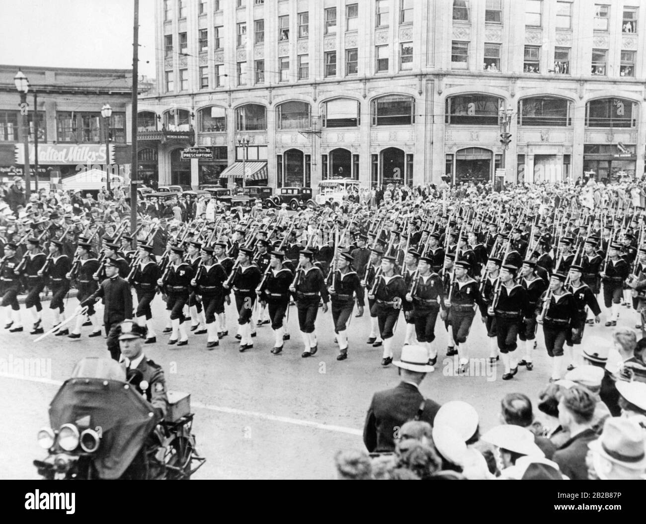 A unit of Japanese sailors marches armed on a street in Seattle in the state of Washington in the U.S. as part of the celebrations marking the independence of the United States on July 4, 1936. The street is lined on both sides with spectators. In front of the sailors drives a policeman on a motorbike. Stock Photo