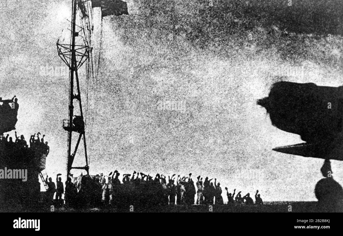 View over the deck of an aircraft carrier of the Imperial Japanese Navy. A bomber is about to take off to join the attack on Pearl Harbor. The crew waves goodbye to it. Stock Photo