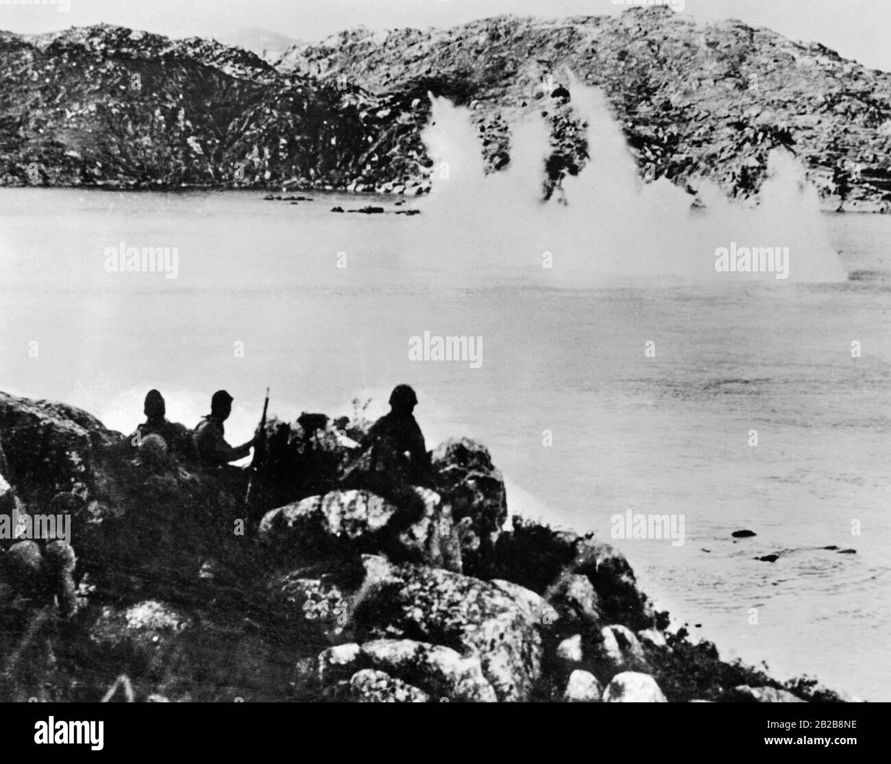 A troop of Japanese soldiers fighting in a bay. On the water an explosion is visible. Stock Photo