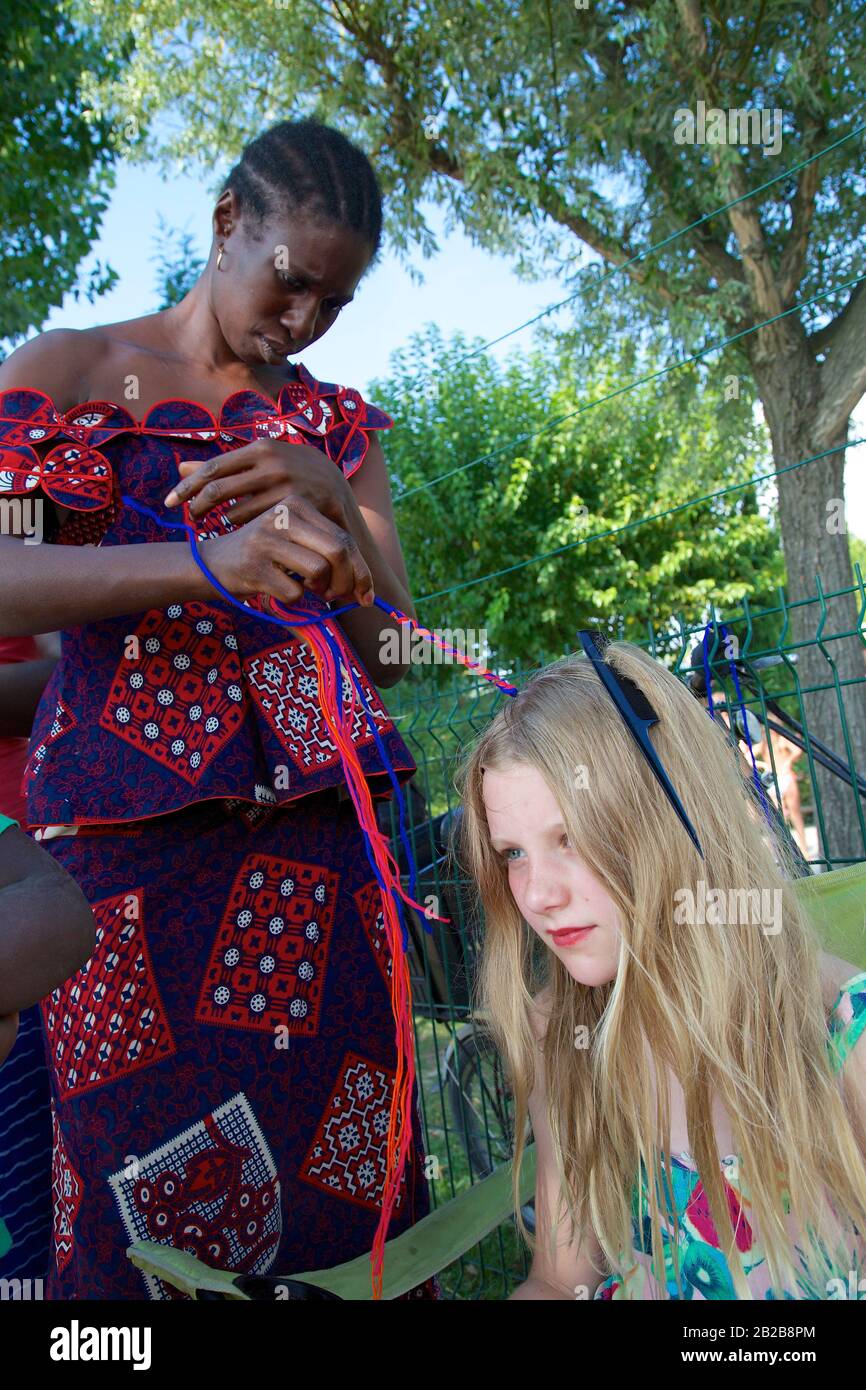 Young girl having hair braided Stock Photo