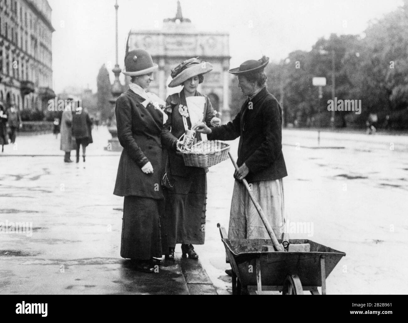 Two ladies of the better society request a donation for the collection box even from the hard working street sweeper on the so-called 'Heckenroeschentag' (Hedge Rose Day). The photo is undated. Stock Photo
