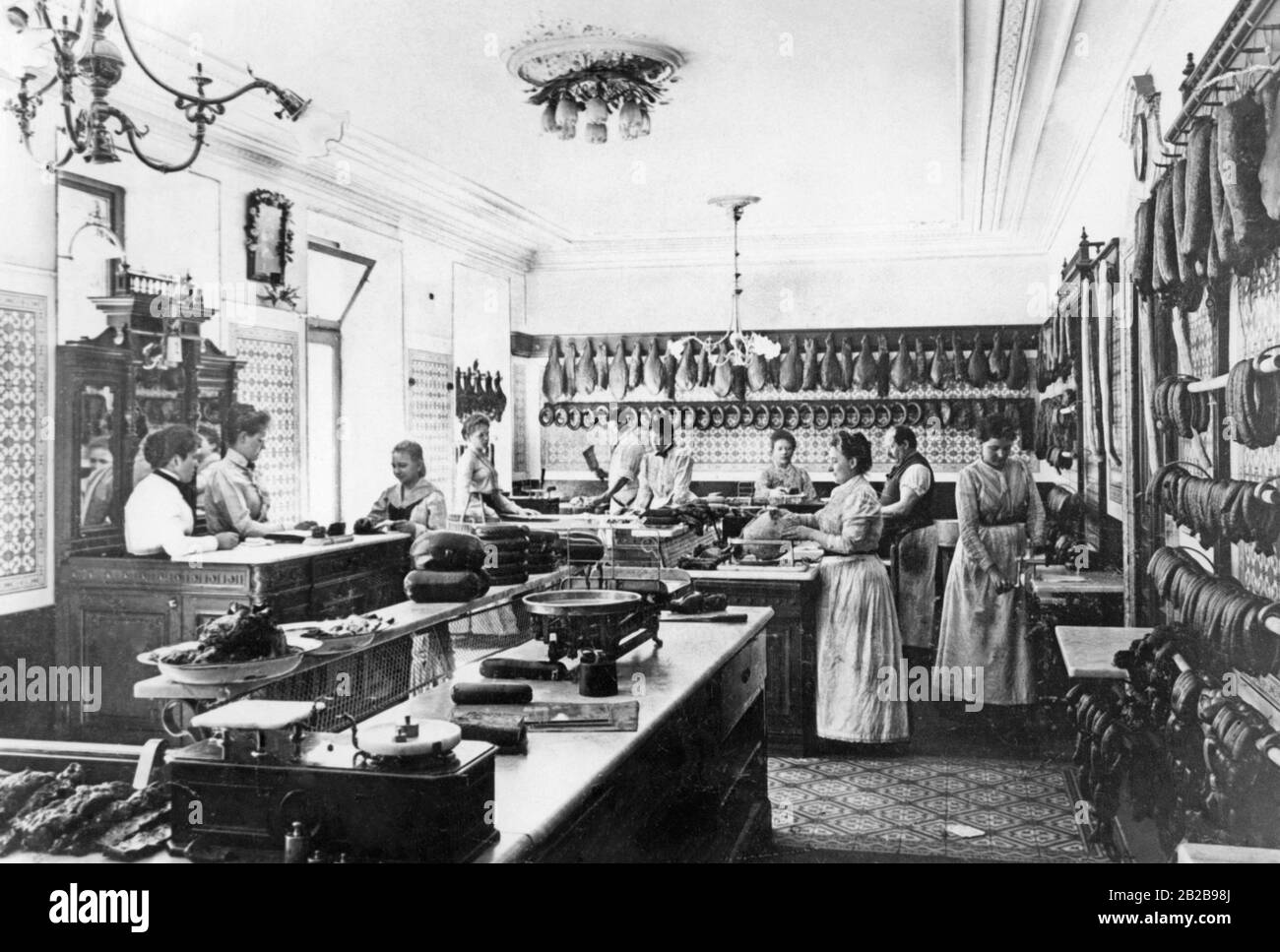 A butcher's shop that was considered the most modern and newest retail store in Berlin at that time. Mostly women work there, left at the cash desk, right as sales assistants. Stock Photo