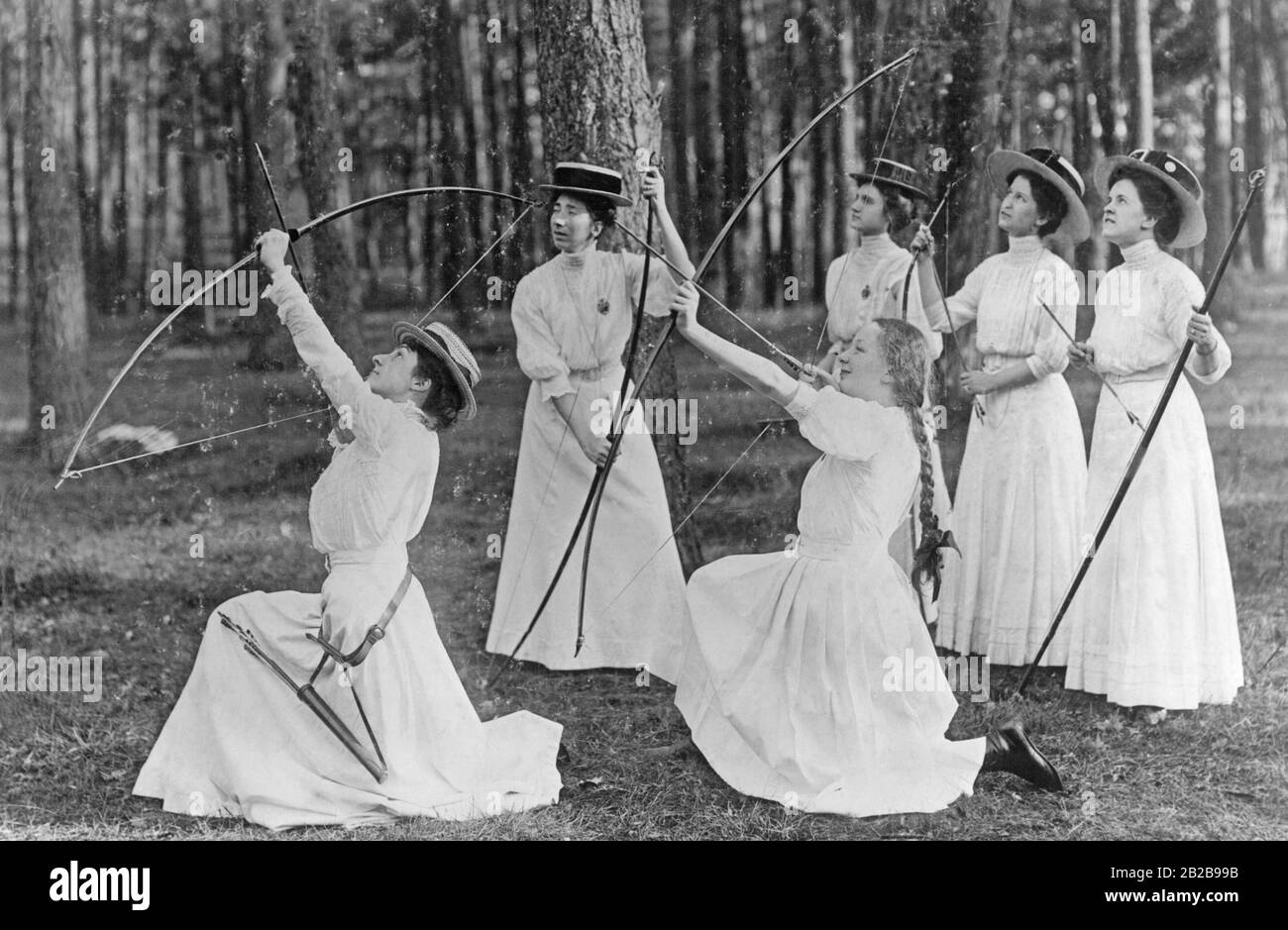 Girl from the upper class shooting gracefully with bow and arrows in the forest. The photo is undated. Stock Photo