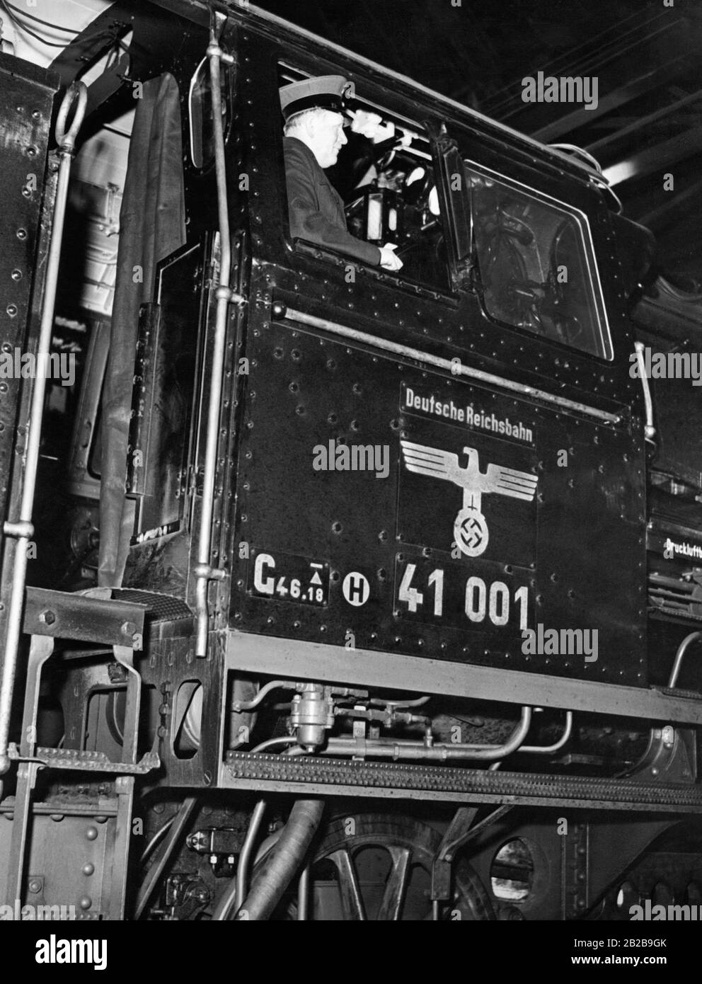 An engineer in the driver's cab of a locomotive of Deutsche Reichsbahn with the number 41001, bearing the Reichsadler (Imperial Eagle) and swastika. Stock Photo