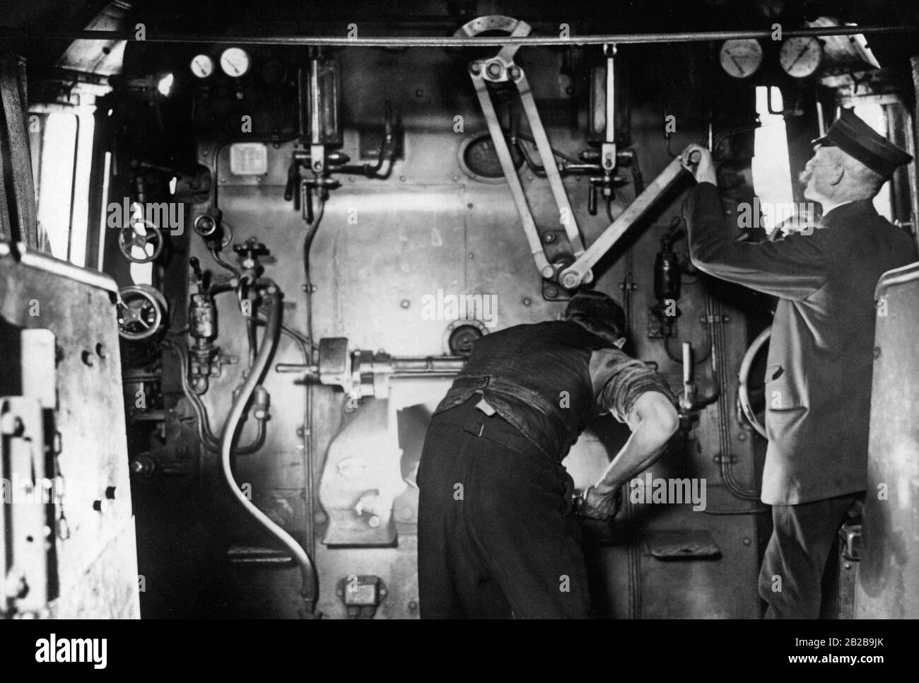 Look in the driver's cab of a steam locomotive. A train driver when operating the mechanical system and a fireman stoking the boiler. Stock Photo