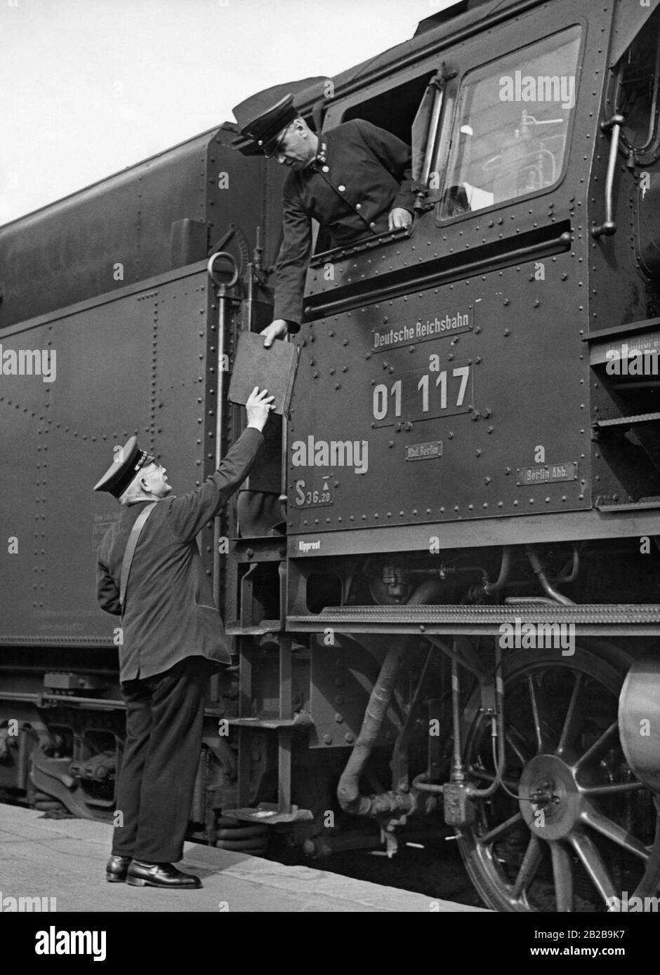 The conductor reports to the locomotive engineer the weight of the train, in other words the number of the attached cars. The picture shows a locomotive of the Deutsche Reichsbahn (German Reich Railway) with the number 01117. Stock Photo
