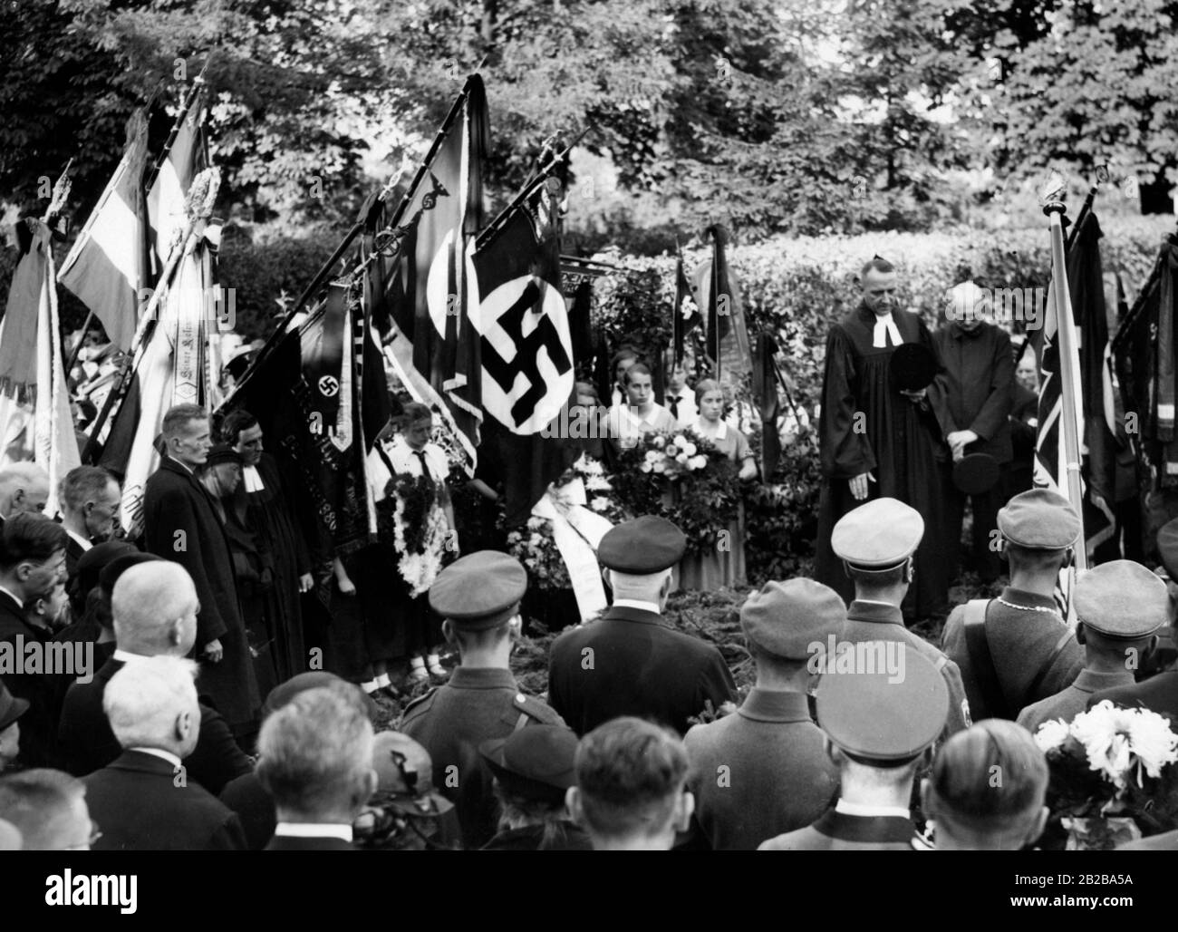 Funeral of the parish priest of Pankow-Niederschoenhausen on 10.09.1934. Next to the tomb are standing flag bearers with swastika flags. Stock Photo