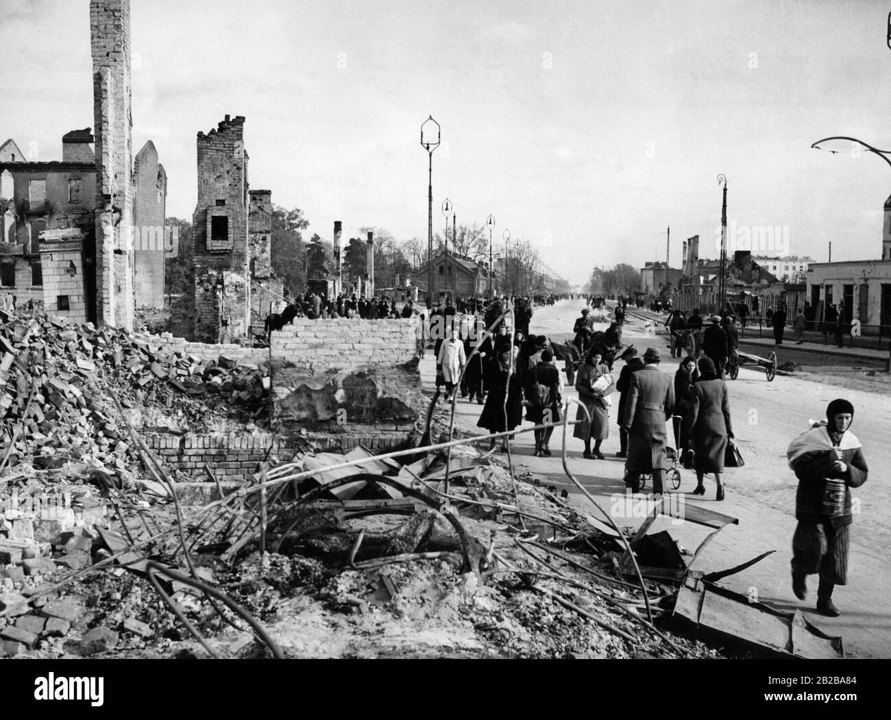 Residents walk past destroyed houses in Warsaw after the end of the fighting. Stock Photo