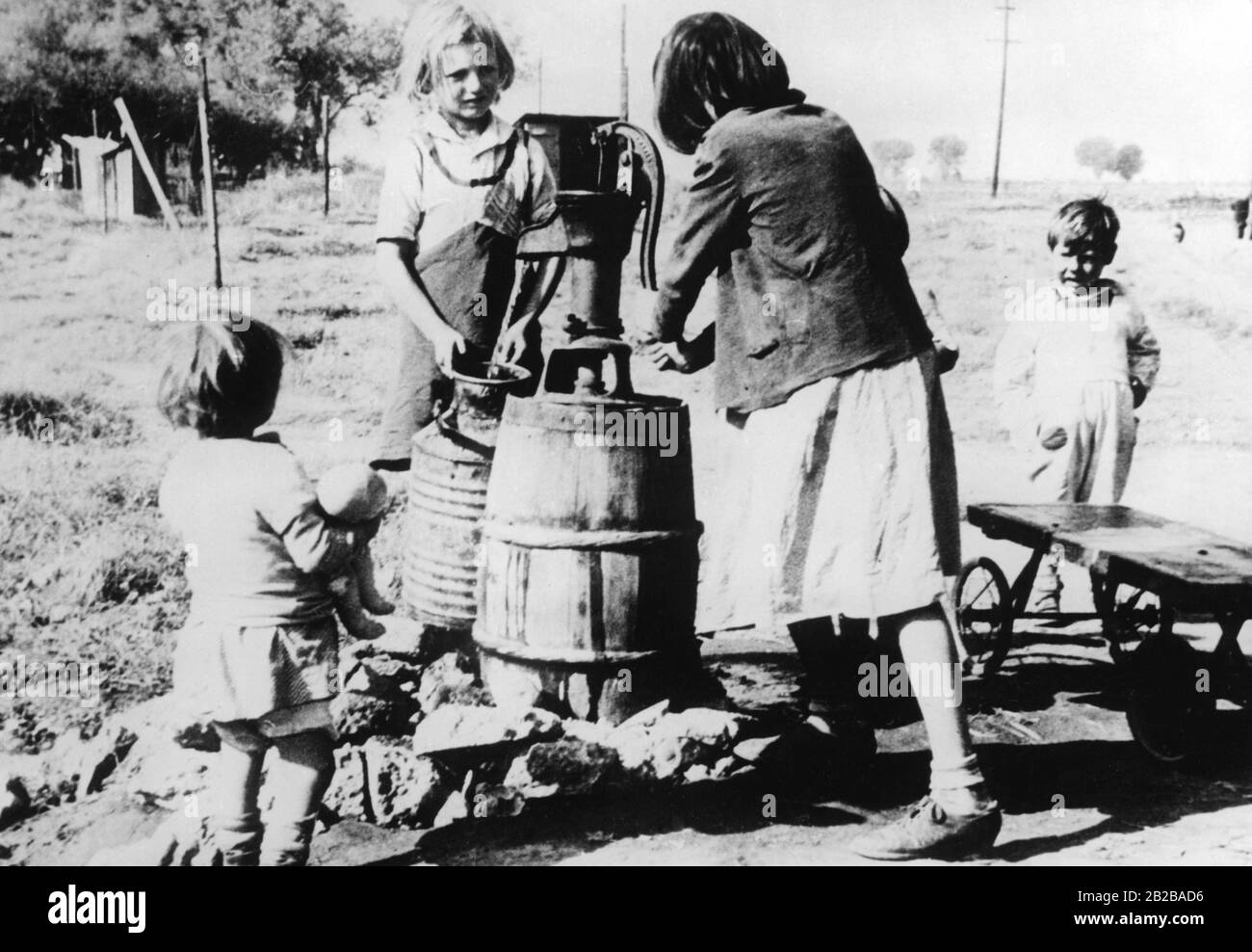 Farmer misery: Unemployed farmhands are homeless. This family pumps water at a well (undated picture). Stock Photo