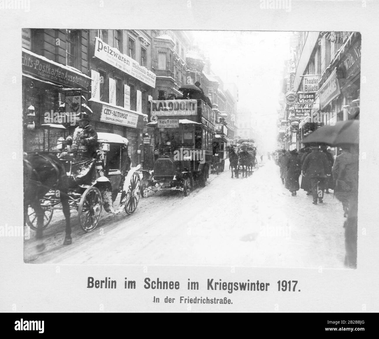 Passers-by walking past the shops in Friedenstrasse in the cold winter of the war, next to the street used by horse-drawn carriages and buses. Stock Photo