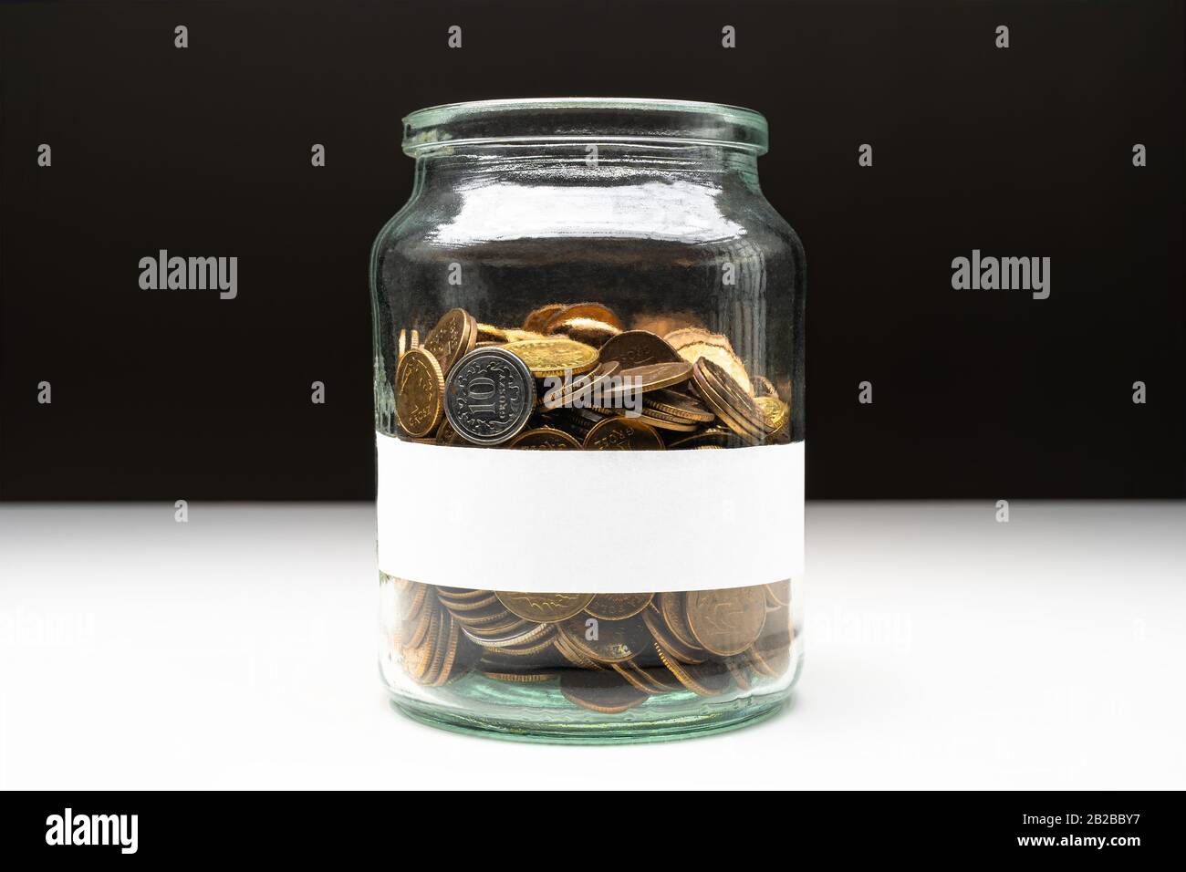 Coins in a jar with blank white label. Savings abstract concept. Copy space. Stock Photo