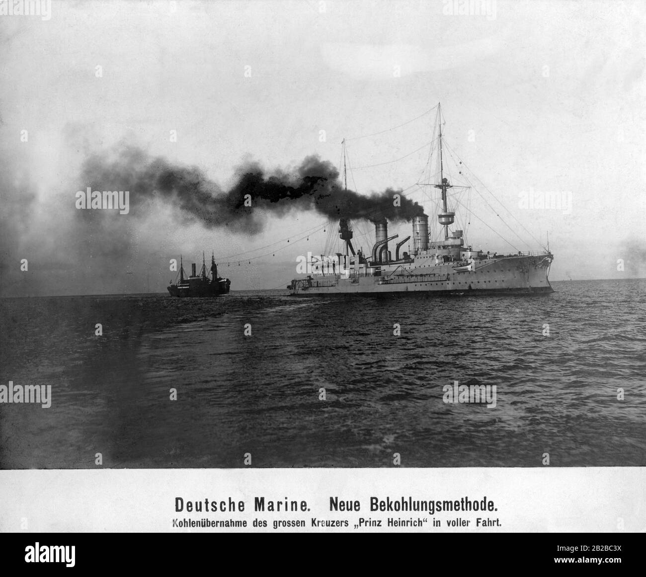The heavy German cruiser 'Prinz Heinrich' on the high seas is practicing with a coaling ship a new method of taking over coal on the high seas. Here an attempt is made to transfer the coal bags from the transport ship to the cruiser by means of a wire rope connection. Stock Photo