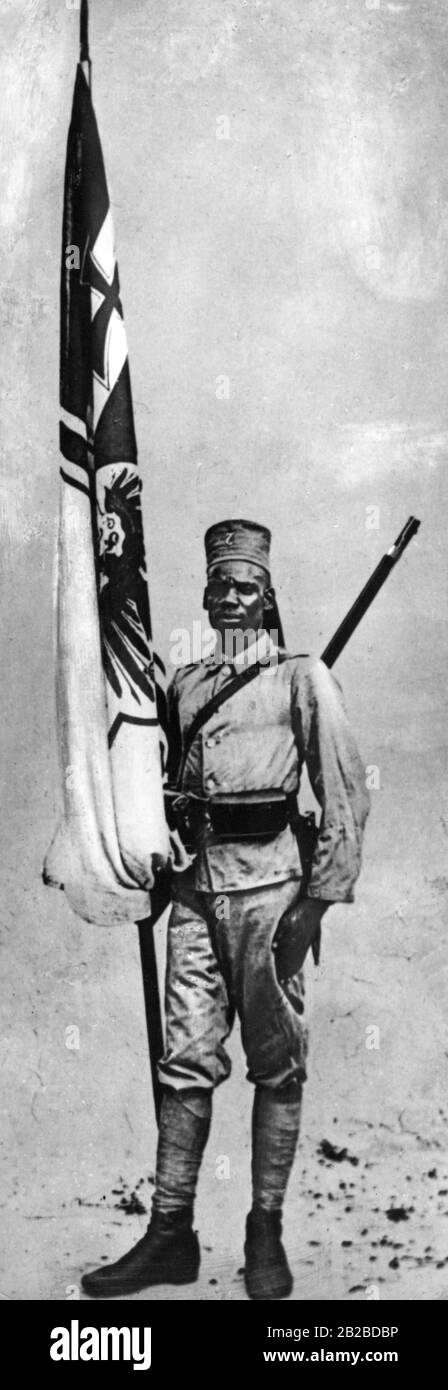 An African standard-bearer in uniform who belongs to the German Schutztruppe, as an Askari, in German East Africa. Native fighters were recruited by the Germans and other colonial powers for their purposes in the colony. Most of them did not wear a complete uniform like the man in the picture. The photo is undated. Stock Photo