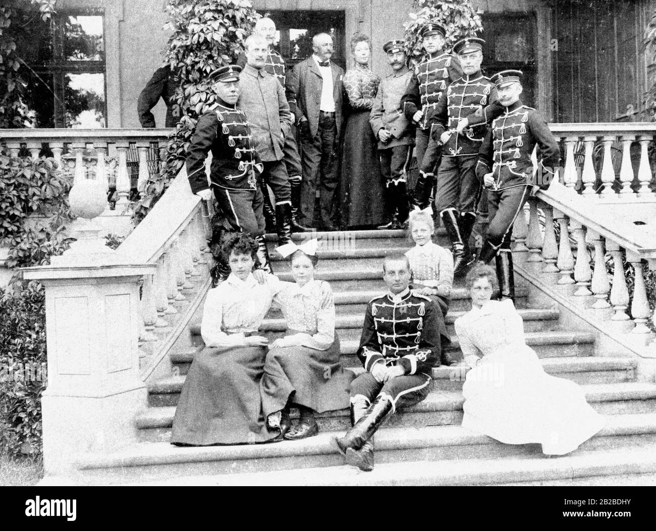 Officers of the Imperial Staff of the Leibhusaren on the Garden estate with the owner's family on the outside staircase of the manor house. The soldiers are there for the annual social event 'Herbstmanoever' (Autumn maneuvers). Stock Photo