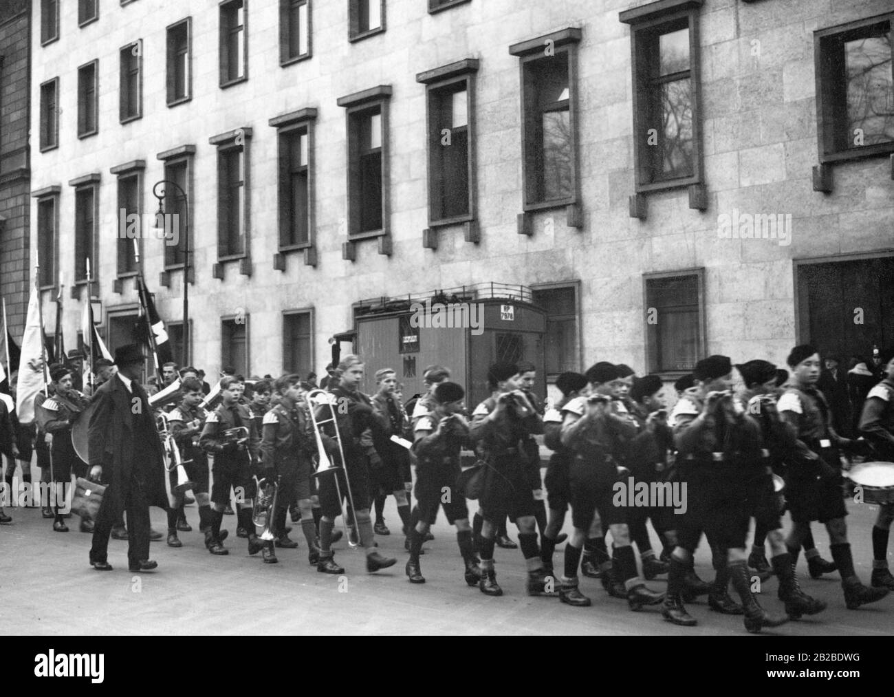 Members of the Hitler Youth march in their uniform in front of the Reich Chancellery with flags, trumpets and drums. Stock Photo